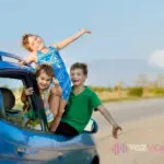 Niños en un coche asomándose por la ventana deseando salir de viaje.