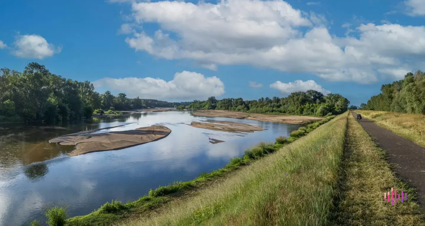 Río de aguas bajas con grandes bancos de arena y un carril bici sobre el dique