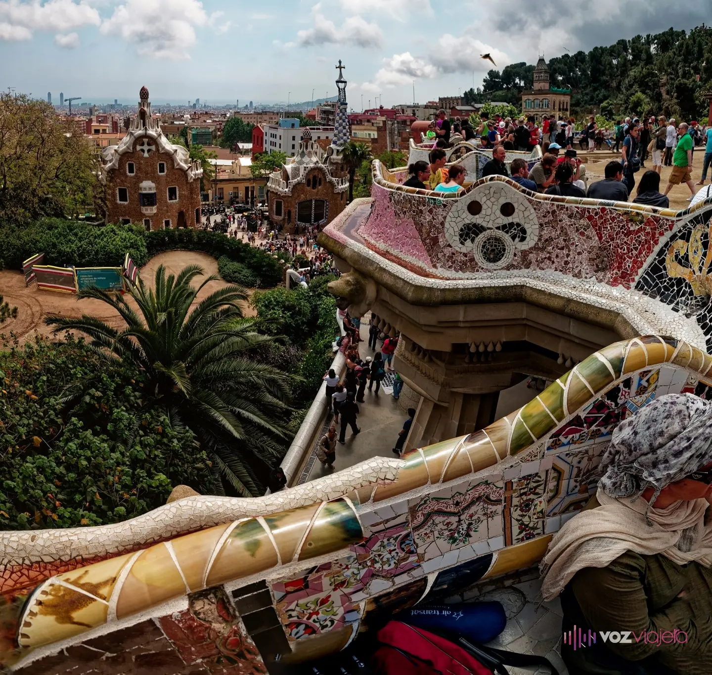 El banco ondulado de trencadís de Jujol recorriendo la plaza de la Naturaleza del Parque Güell, con Barcelona al fondo