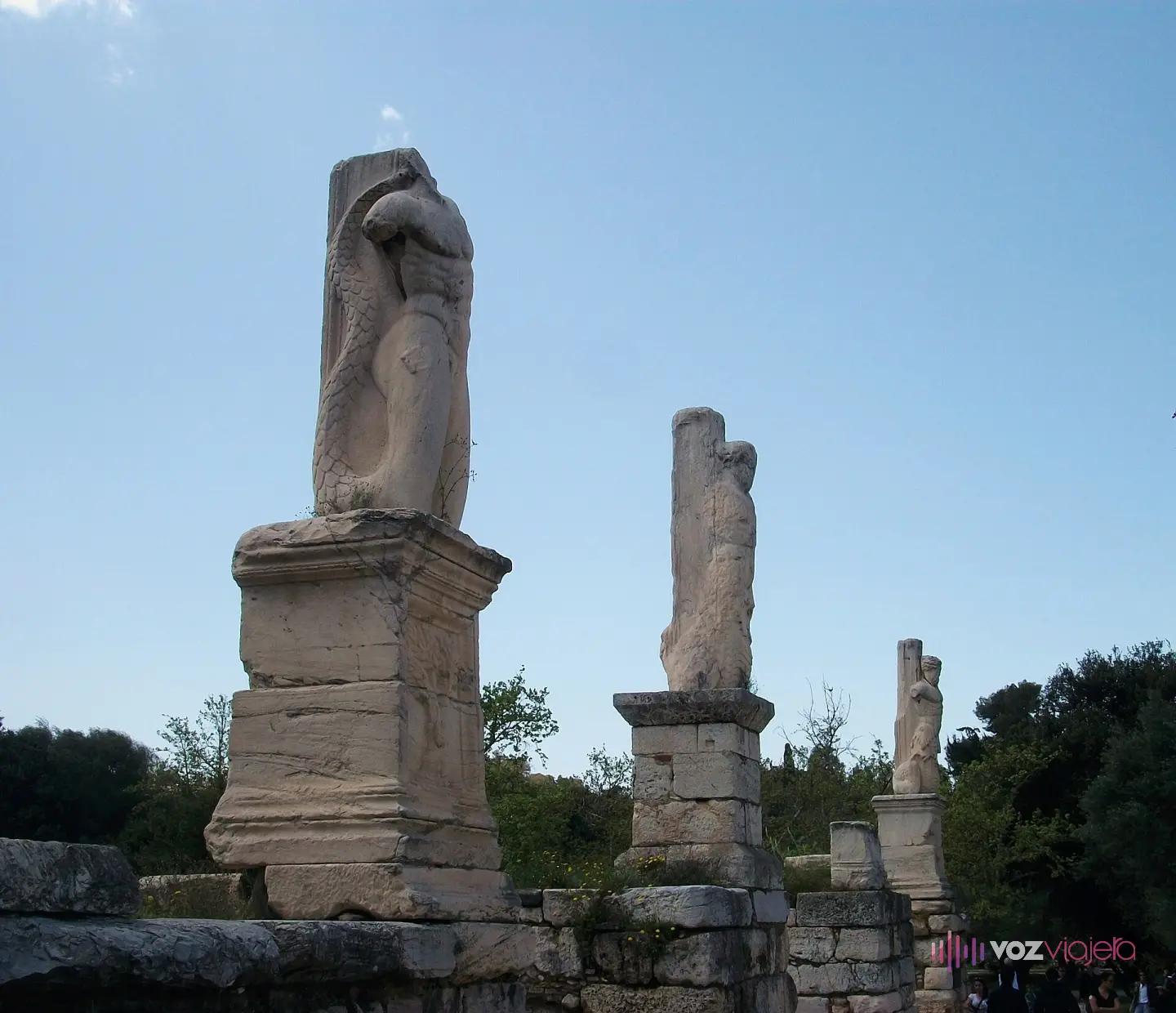 Tres pilares esculpidos con forma de gigantes y tritones, restos de la fachada del Odeón de Agripa, alzados sobre sus pedestales contra el cielo del Ágora de Atenas
