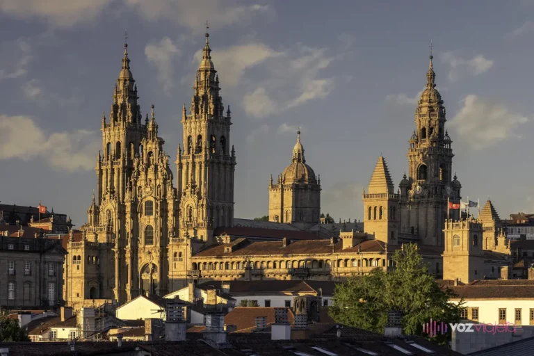 La catedral de Santiago de Compostela vista desde el parque de la Alameda al atardecer: las torres barrocas del Obradoiro y la cúpula sobre los tejados del casco viejo
