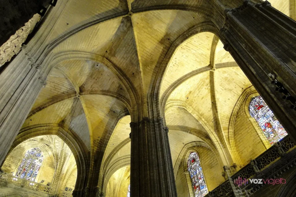 Bóvedas de crucería y pilares góticos del interior de la Catedral de Sevilla vistos desde abajo, con luz entrando por las vidrieras