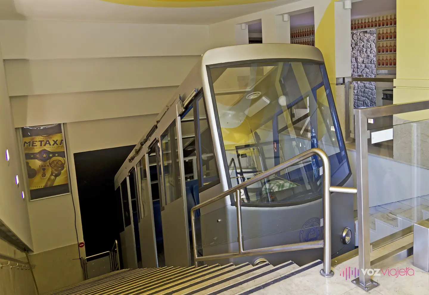 El vagón del funicular del Licabeto detenido en la estación de arriba, dentro del túnel excavado en la roca, junto a la escalera por la que suben y bajan los viajeros