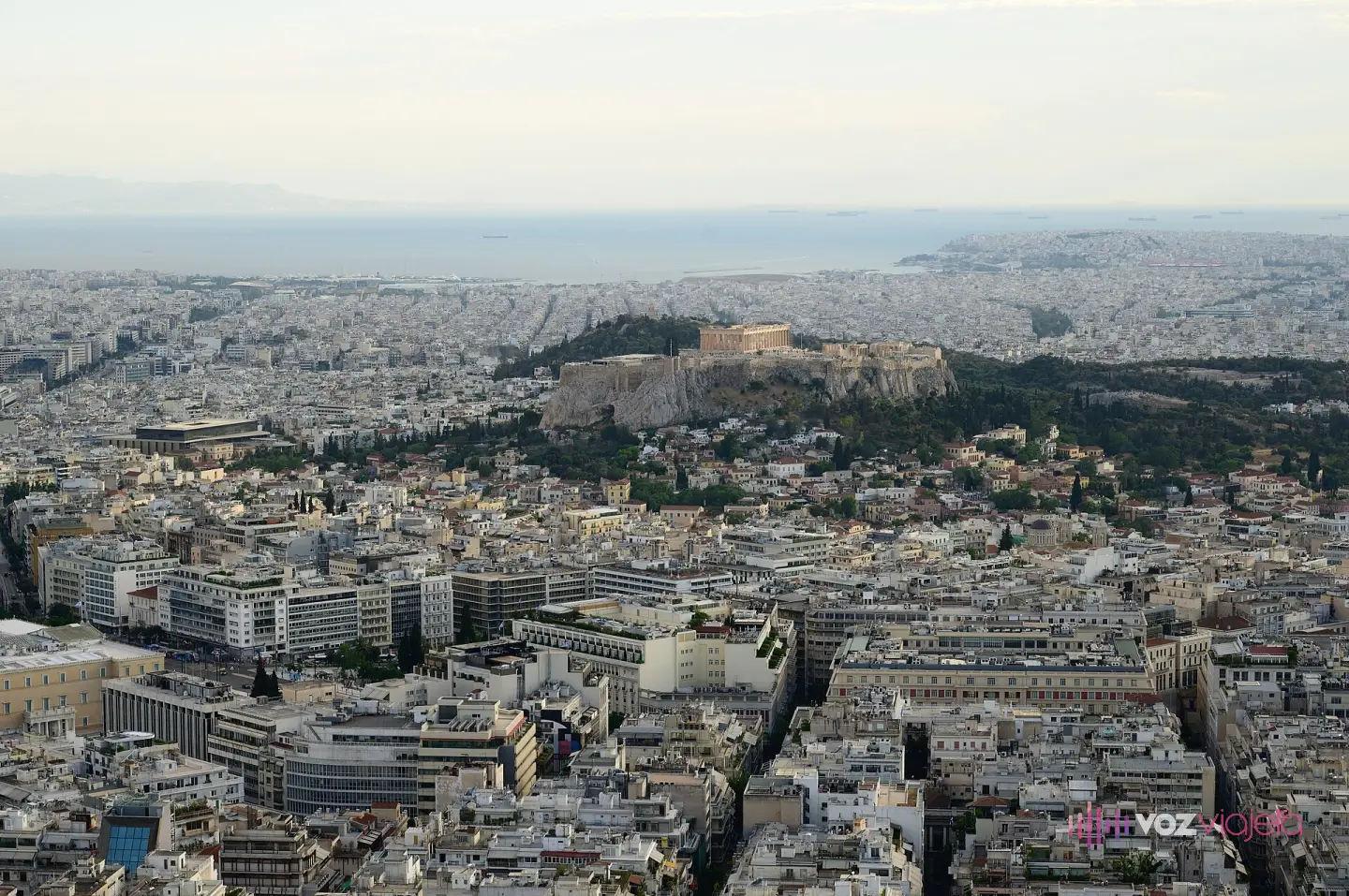 Panorámica de Atenas desde la cima del monte Licabeto: el mar de azoteas blancas del centro, la roca de la Acrópolis con el Partenón encima y, al fondo, la costa del golfo Sarónico