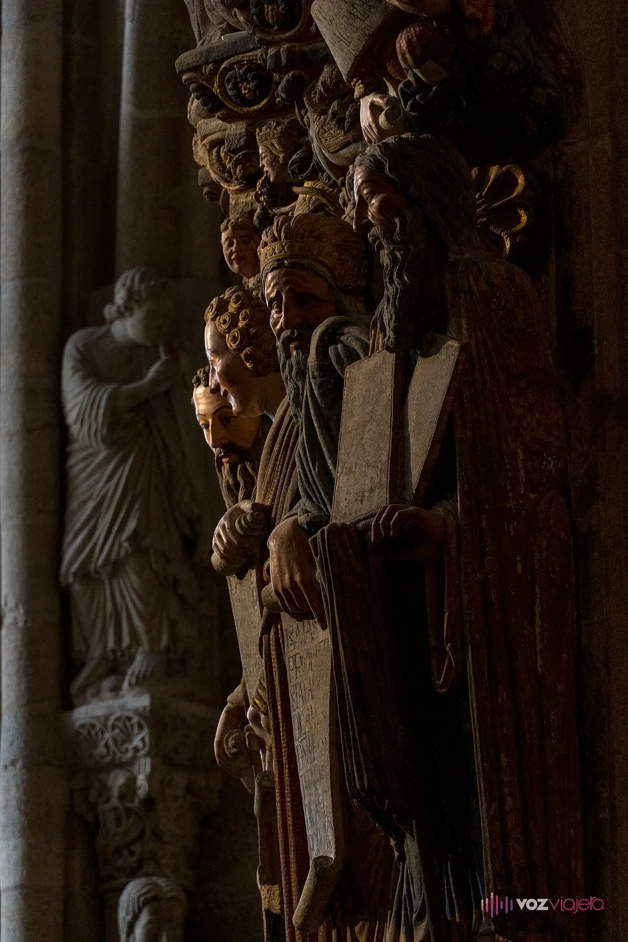 Detalle del Pórtico de la Gloria: estatuas-columna de granito con restos de policromía roja y dorada, en la penumbra de la entrada occidental de la catedral