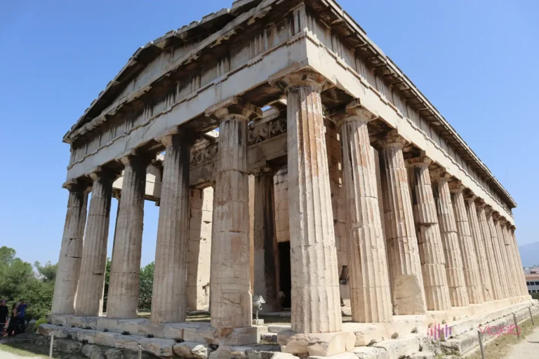 El Templo de Hefesto de Atenas entero, visto en escorzo desde una esquina: el frontón triangular, las columnas dóricas de la fachada y las de todo el flanco, con el entablamento y parte de la cubierta todavía en su sitio