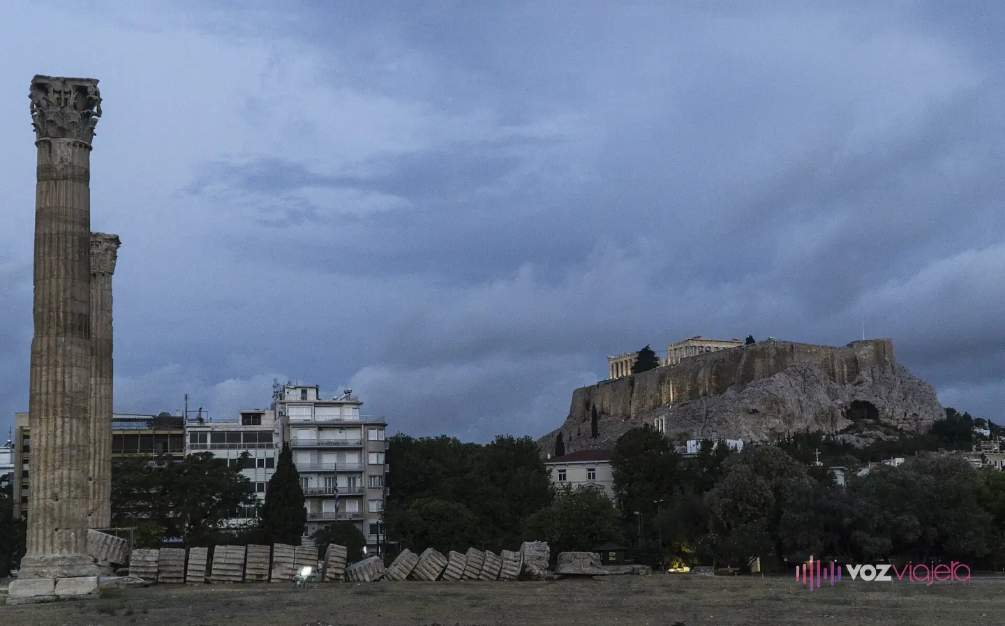 El Templo de Zeus Olímpico al atardecer con la roca de la Acrópolis y el Partenón iluminados al fondo