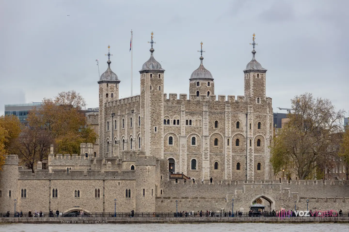 La Torre Blanca de la Torre de Londres vista desde el Támesis: un torreón cuadrado de piedra gris con almenas y 4 torretas rematadas en cúpulas de plomo y veletas, detrás de la muralla exterior; en el muelle, abajo a la izquierda, el rótulo «Entry to the Traitors Gate» sobre un arco a ras del agua