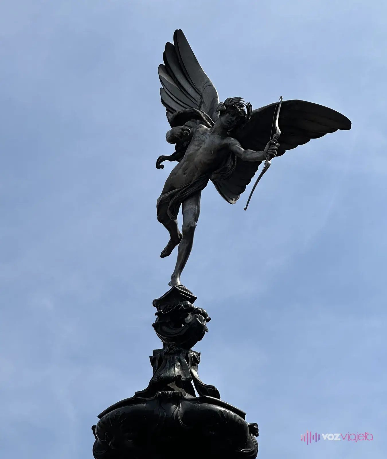 Estatua alada de Anteros, con el arco en la mano, sobre lo alto de la fuente y contra el cielo