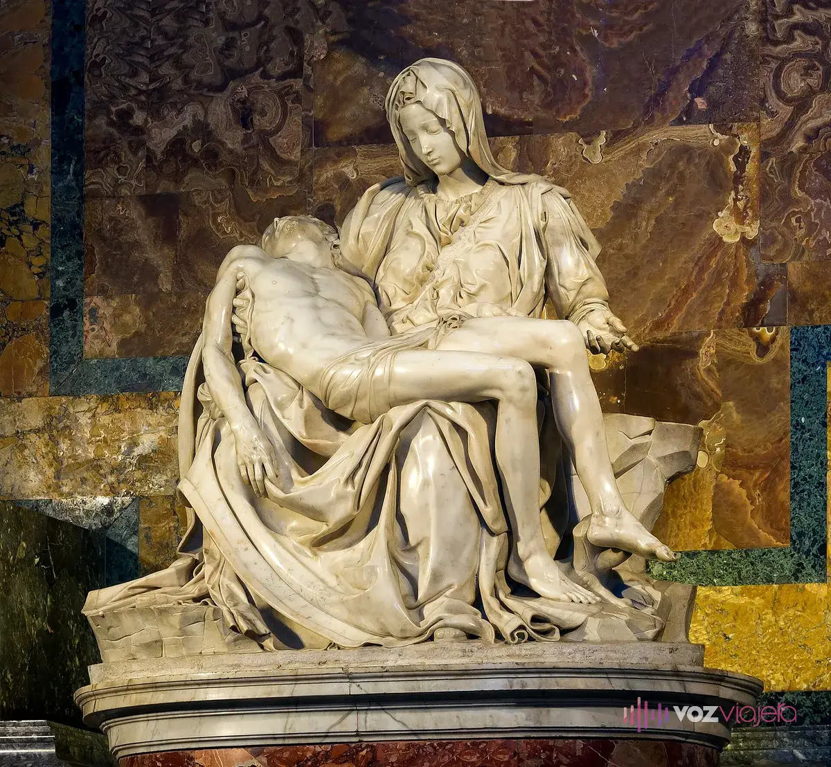 La Piedad de Miguel Ángel en la Basílica de San Pedro: la Virgen de mármol blanco sentada sostiene sobre las rodillas a Cristo muerto, ante un fondo de mármoles de colores