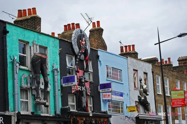Fachadas pintadas de Camden High Street con figuras gigantes sobre las tiendas: unas piernas con botas, una mujer y un gorila