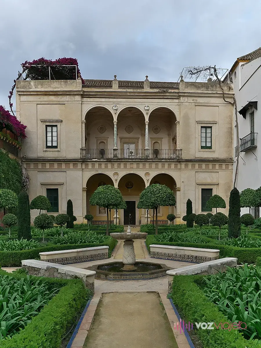 Logia del Jardín Grande de la Casa de Pilatos: galería de arcos en 2 plantas al fondo de un jardín de setos recortados con una fuente de pilón octogonal en el centro