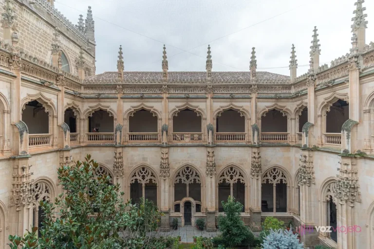 El claustro de San Juan de los Reyes desde el jardín, con sus 2 pisos de arcos góticos, la crestería y los pináculos sobre el tejado