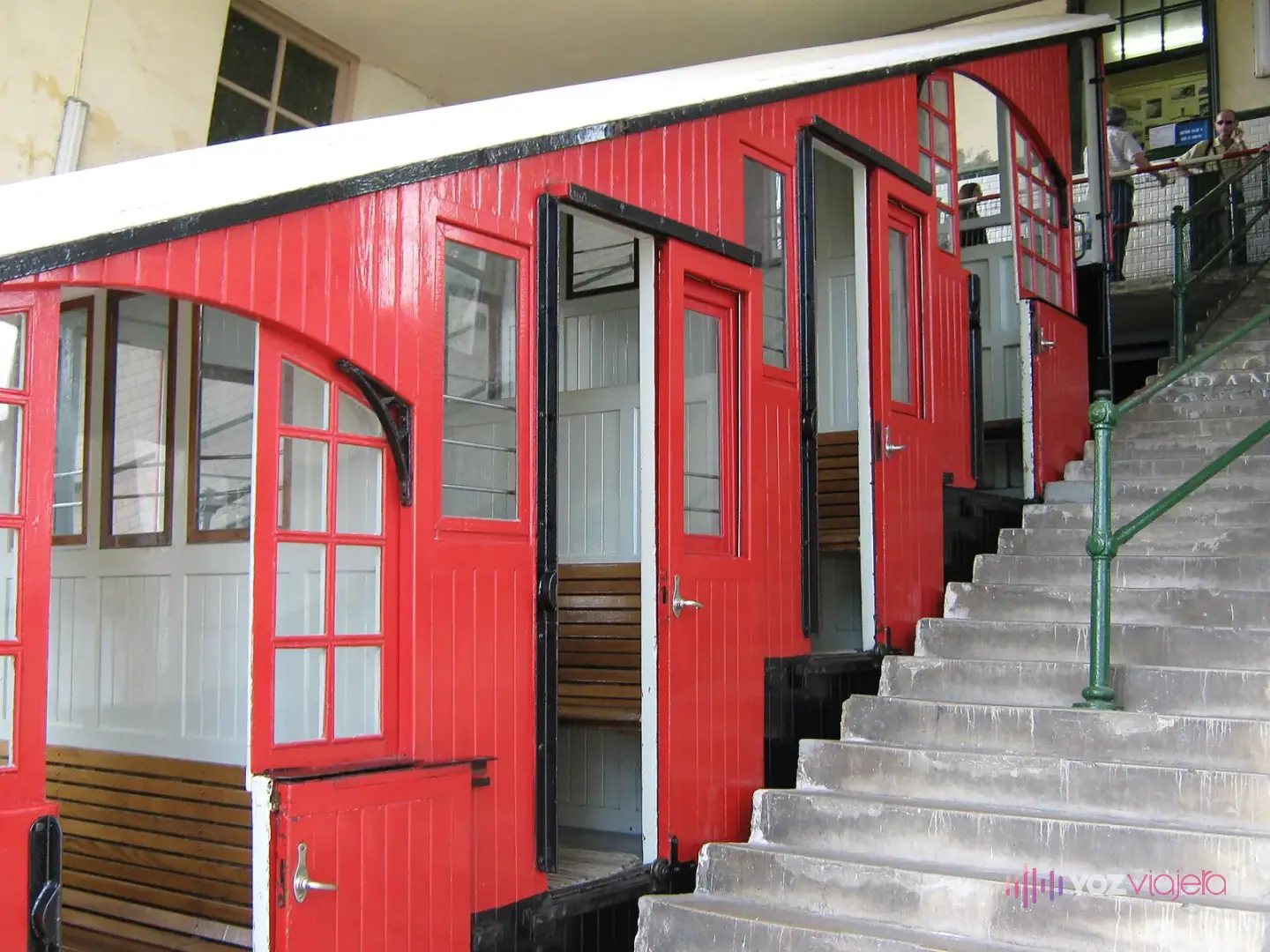 Vagón rojo de madera del funicular de Igueldo en la estación superior, con sus compartimentos escalonados y la escalera del andén al lado