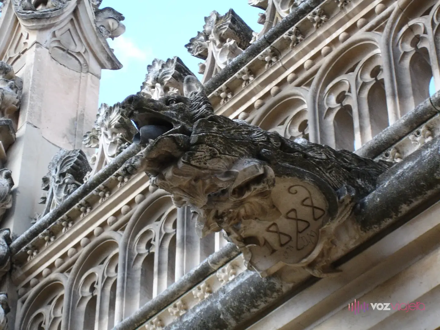 Una gárgola de piedra con forma de lobo en el claustro de San Juan de los Reyes; en el escudo que sujeta se lee el año 1888
