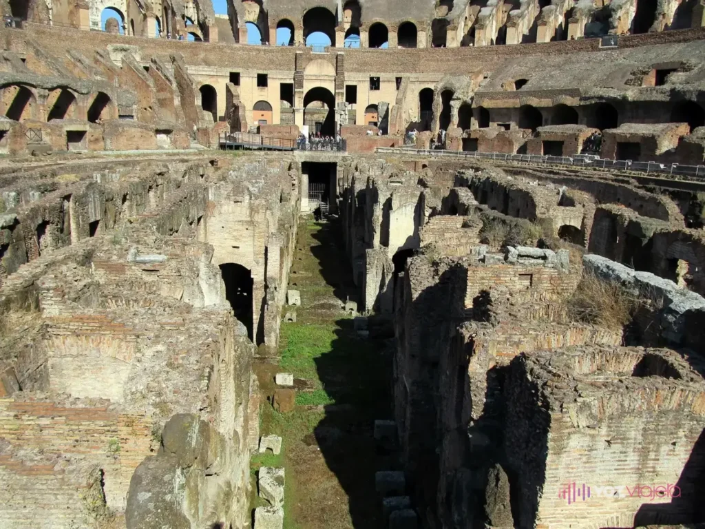 Los subterráneos del Coliseo vistos de cerca: muros paralelos de ladrillo y piedra con pasillos estrechos entre ellos, por debajo del nivel de la arena