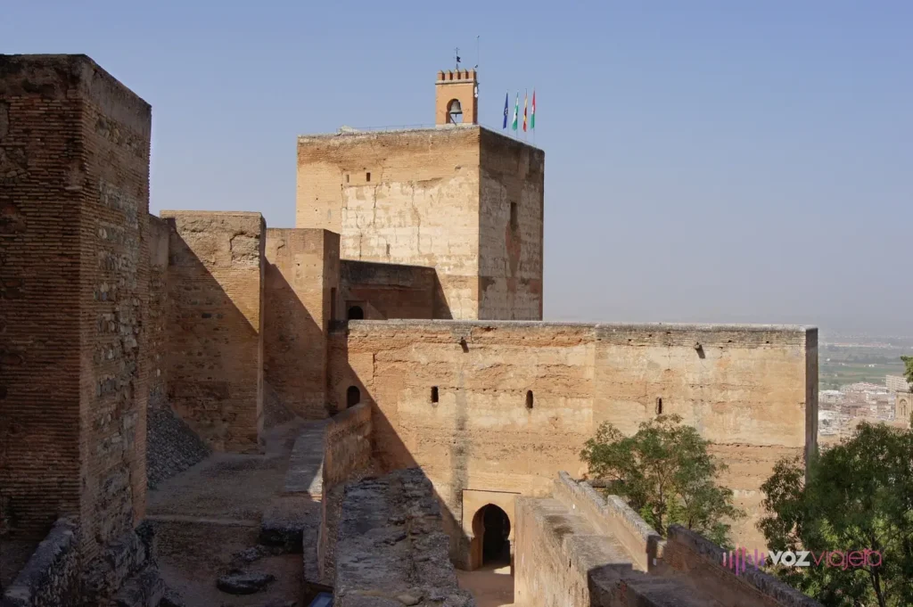 Las murallas de la Alcazaba de la Alhambra con la Torre de la Vela al fondo, rematada por su campana y varias banderas