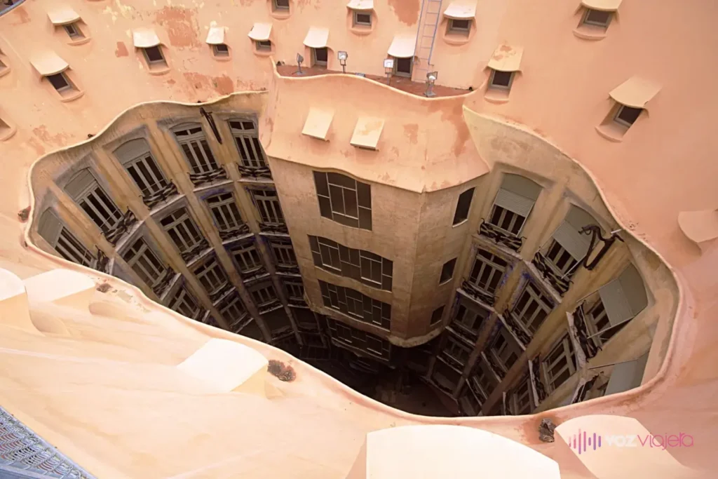 Uno de los 2 patios interiores de La Pedrera visto desde la azotea: un hueco ovalado e irregular rodeado de ventanitas del desván, con las ventanas y balcones de los pisos bajando hasta la planta baja