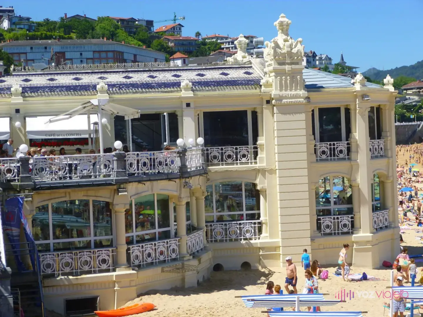 El edificio color crema de La Perla, con balcones blancos de hierro, levantado sobre la arena de La Concha entre bañistas