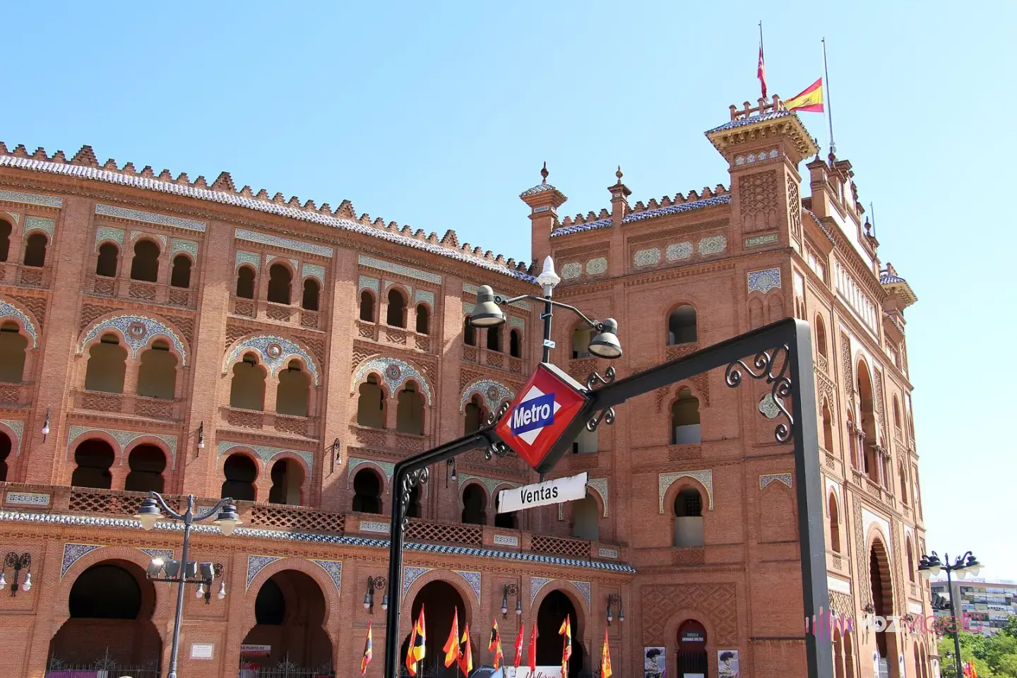 Boca de la estación de metro Ventas con su rótulo rojo y azul delante de la fachada de la plaza de toros