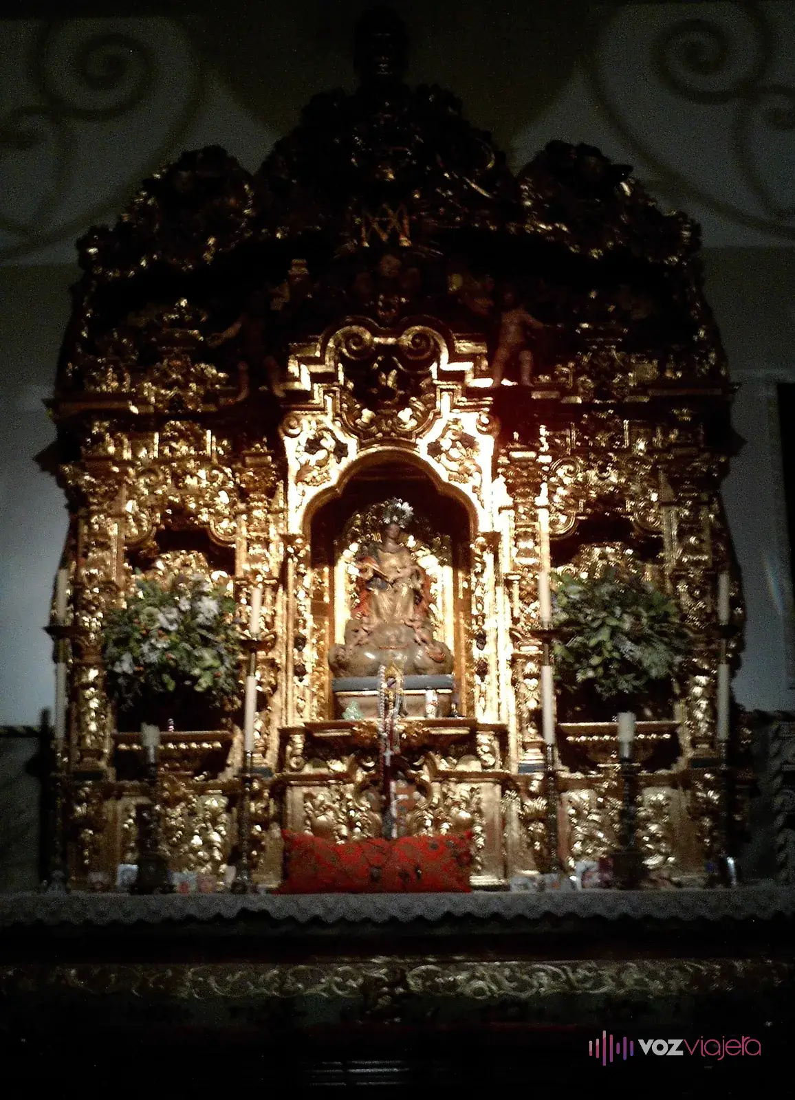 Retablo dorado de la Capilla de los Toreros de la plaza de toros de la Maestranza de Sevilla, con la imagen de la Virgen en el centro y flores a los lados