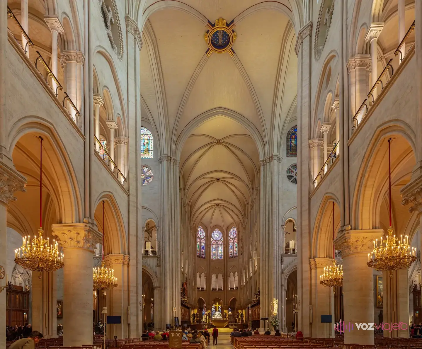 Nave central de Notre Dame de París restaurada, con la piedra clara, bóvedas de crucería, lámparas de araña y el coro al fondo