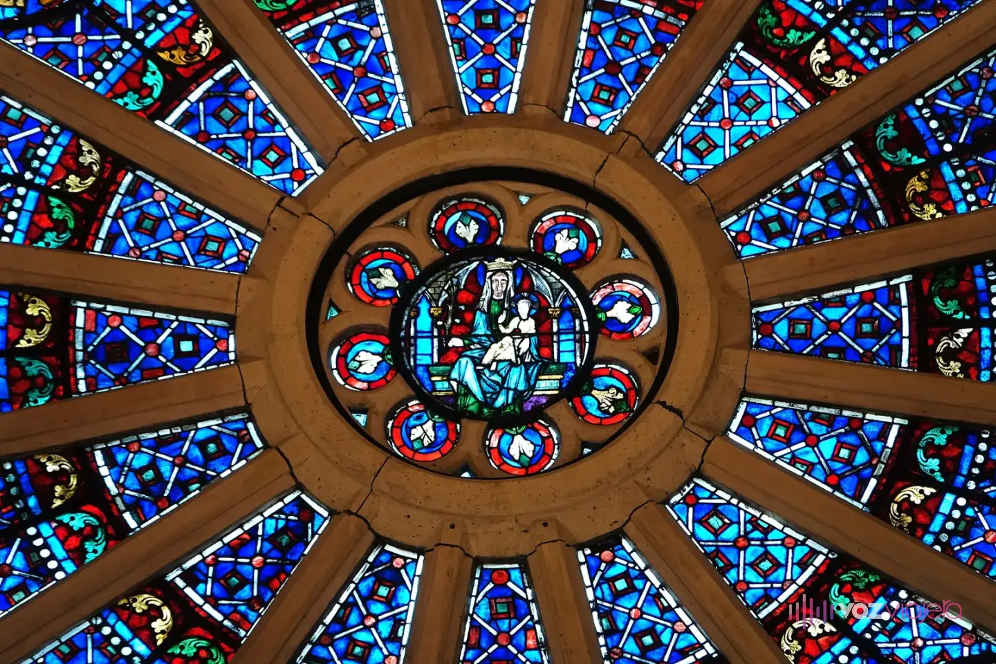El rosetón norte de Notre Dame visto desde dentro, con vidrieras azules y rojas en círculos alrededor de una figura central