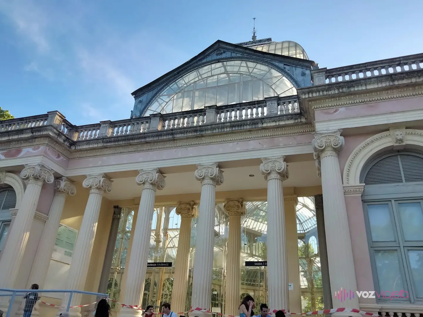 Pórtico de entrada del Palacio de Cristal: columnas jónicas blancas bajo una balaustrada, con la bóveda de vidrio detrás