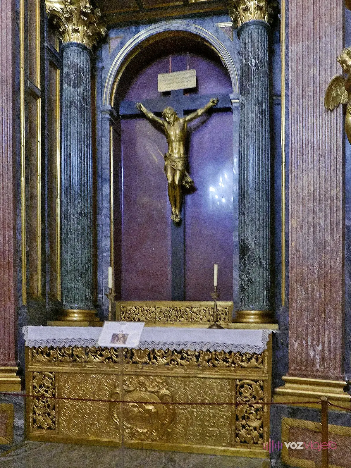 Altar del Panteón de los Reyes de El Escorial: un Cristo crucificado entre columnas de mármol y una mesa de altar de bronce dorado
