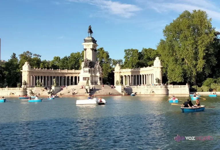 Estanque Grande del Retiro con barcas de remo azules y, al fondo, la columnata semicircular del monumento a Alfonso XII con la estatua ecuestre en lo alto