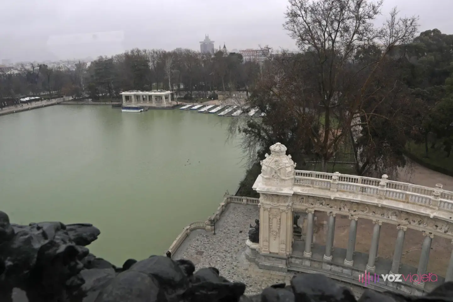 El Estanque Grande visto desde lo alto del monumento a Alfonso XII, con esculturas de bronce en primer plano y el embarcadero al otro lado del agua