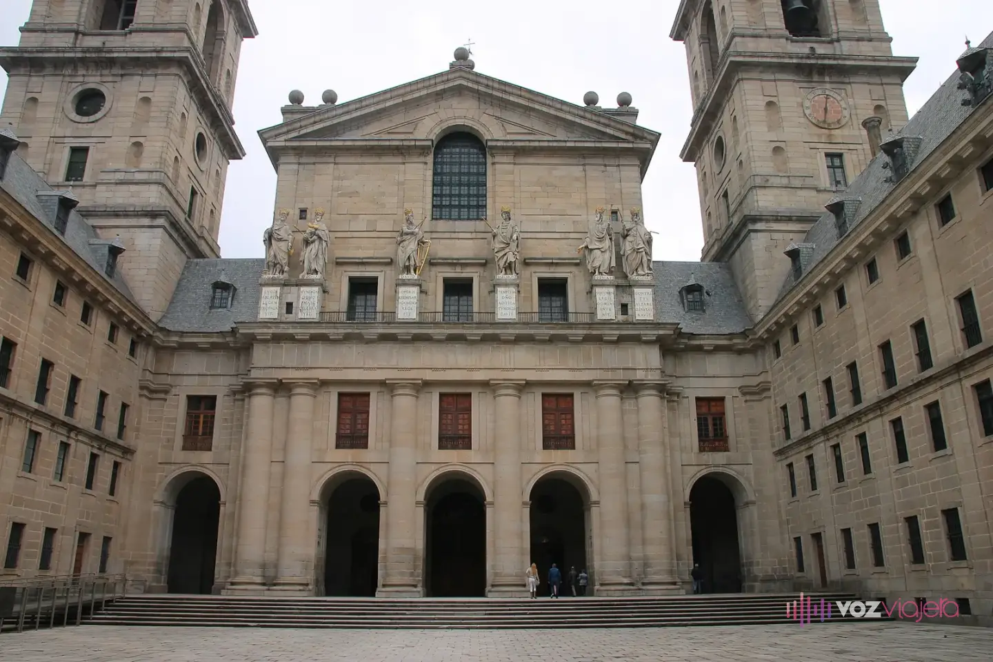 Patio de los Reyes de El Escorial: la fachada de la basílica con sus dos torres, el frontón y las estatuas de reyes, y los muros de granito del patio
