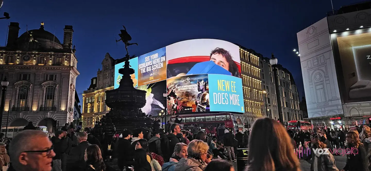 Piccadilly Circus de noche, con la pantalla curva iluminada, la fuente a contraluz y mucha gente en la plaza