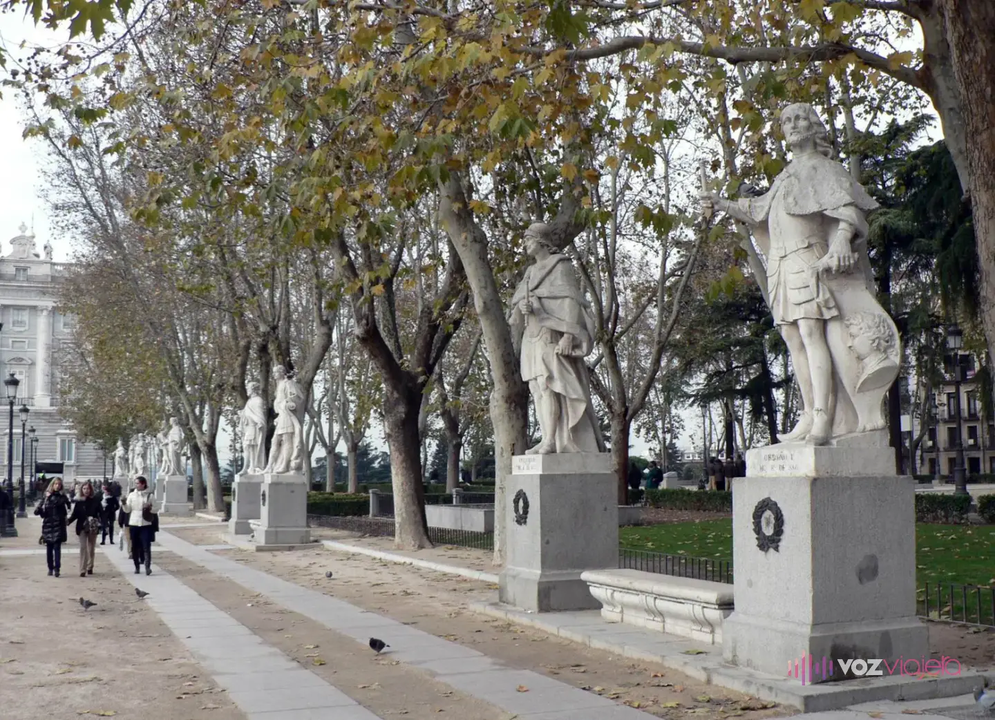 Una de las hileras de estatuas de reyes de piedra de la Plaza de Oriente, sobre pedestales, bajo los plátanos del paseo