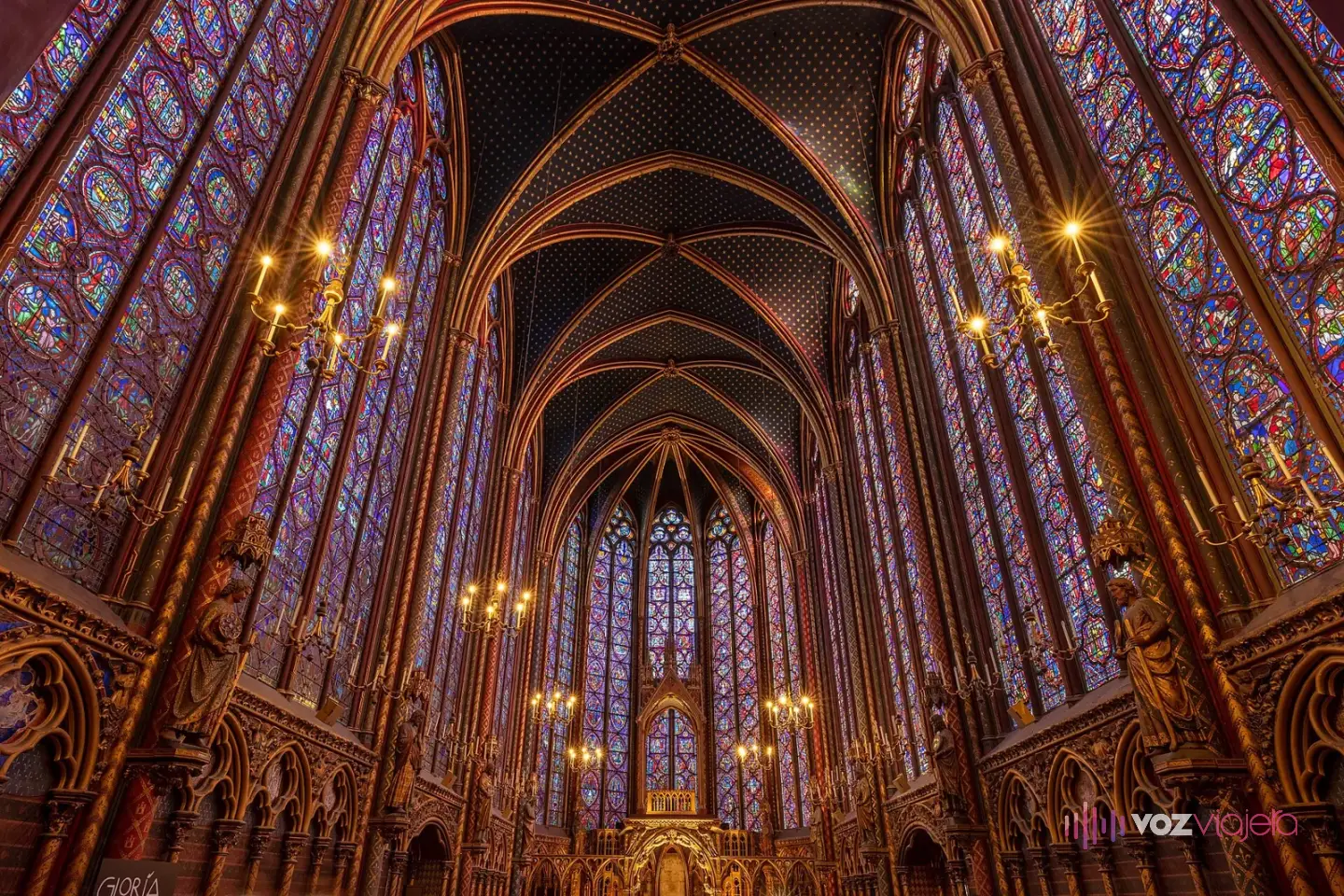 Interior de la capilla alta de la Sainte-Chapelle: muros de vidrieras azules y rojas hasta la bóveda, columnas doradas y el ábside al fondo