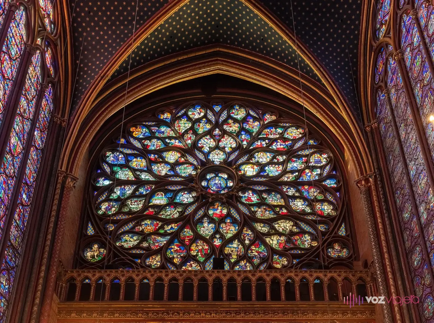 El rosetón del Apocalipsis de la Sainte-Chapelle visto desde dentro, con vidrieras de tonos verdes, amarillos y azules en tracería flamígera