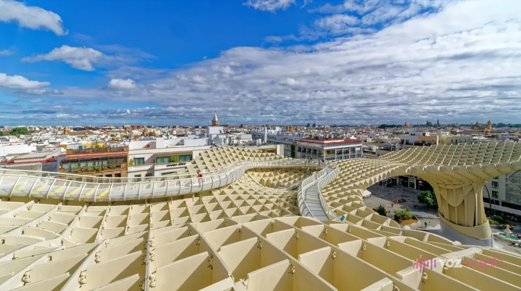 Las pasarelas sobre la cubierta de las Setas de Sevilla, con la retícula de madera en primer plano y los tejados de Sevilla al fondo bajo un cielo con nubes
