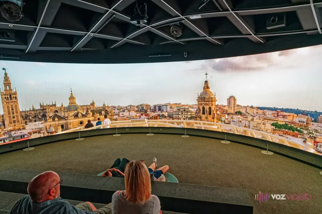 Sala de proyección panorámica del Metropol Parasol: el público sentado ante una pantalla curva que muestra la Giralda y los tejados de Sevilla