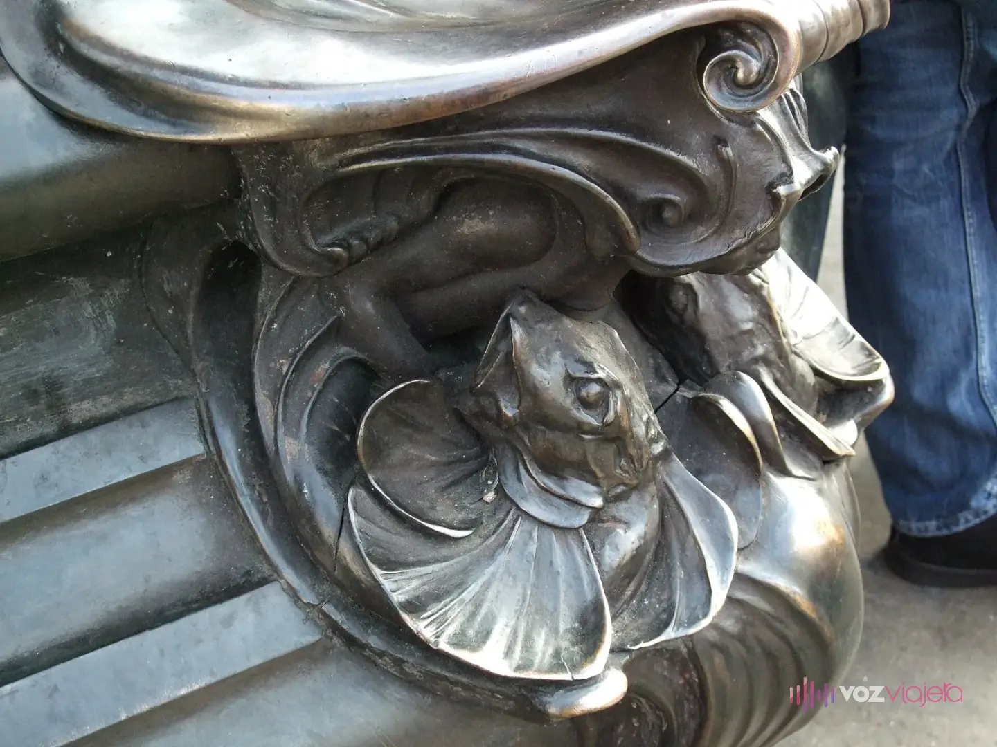 Detalle de bronce de la base de la fuente: una criatura marina sobre una concha, entre volutas