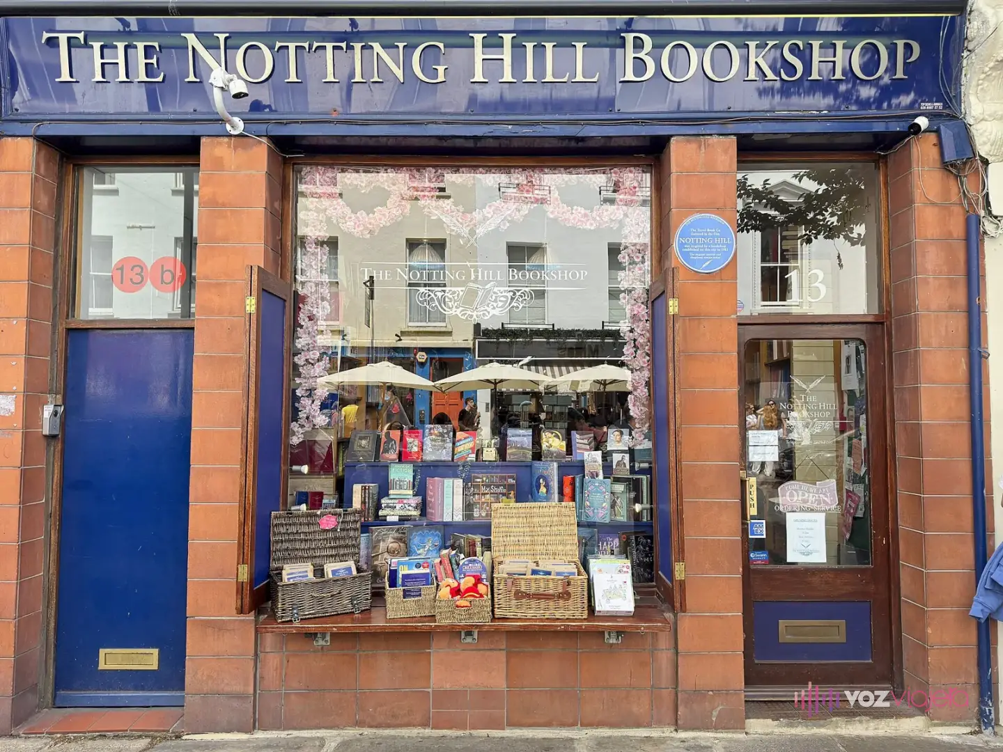 Escaparate de The Notting Hill Bookshop, con su rótulo azul de letras doradas, pilares de azulejo terracota y una placa azul en la fachada