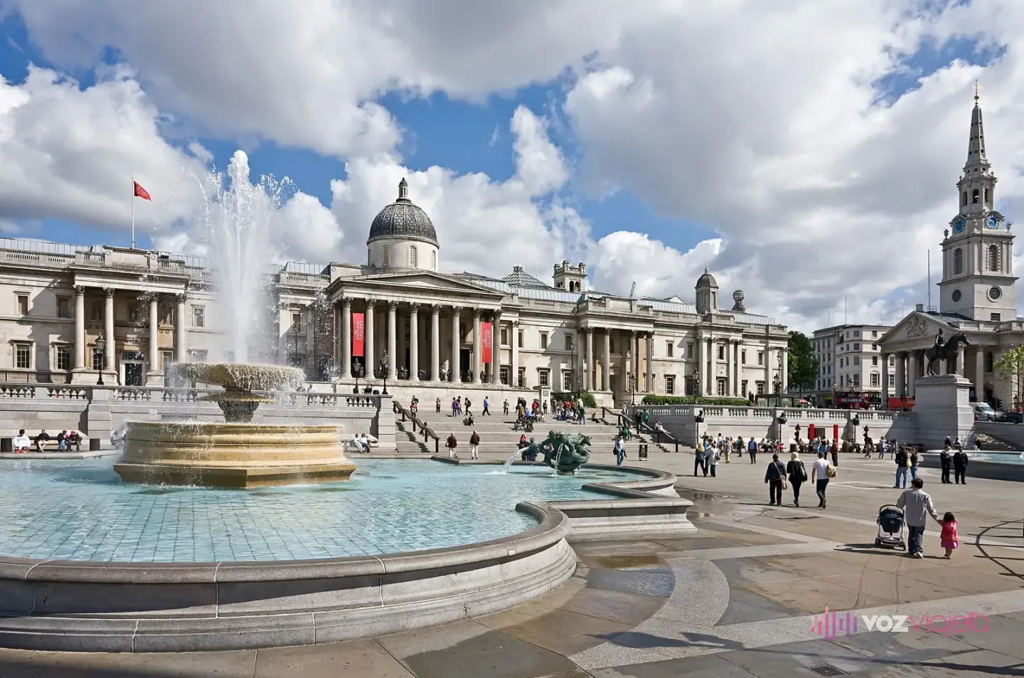 Trafalgar Square con una de sus fuentes en primer plano y, al fondo, la fachada con cúpula de la National Gallery y la torre de St Martin-in-the-Fields